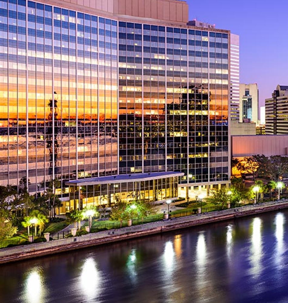 The downtown Jacksonville skyline at dusk, reflected in the St. Johns River